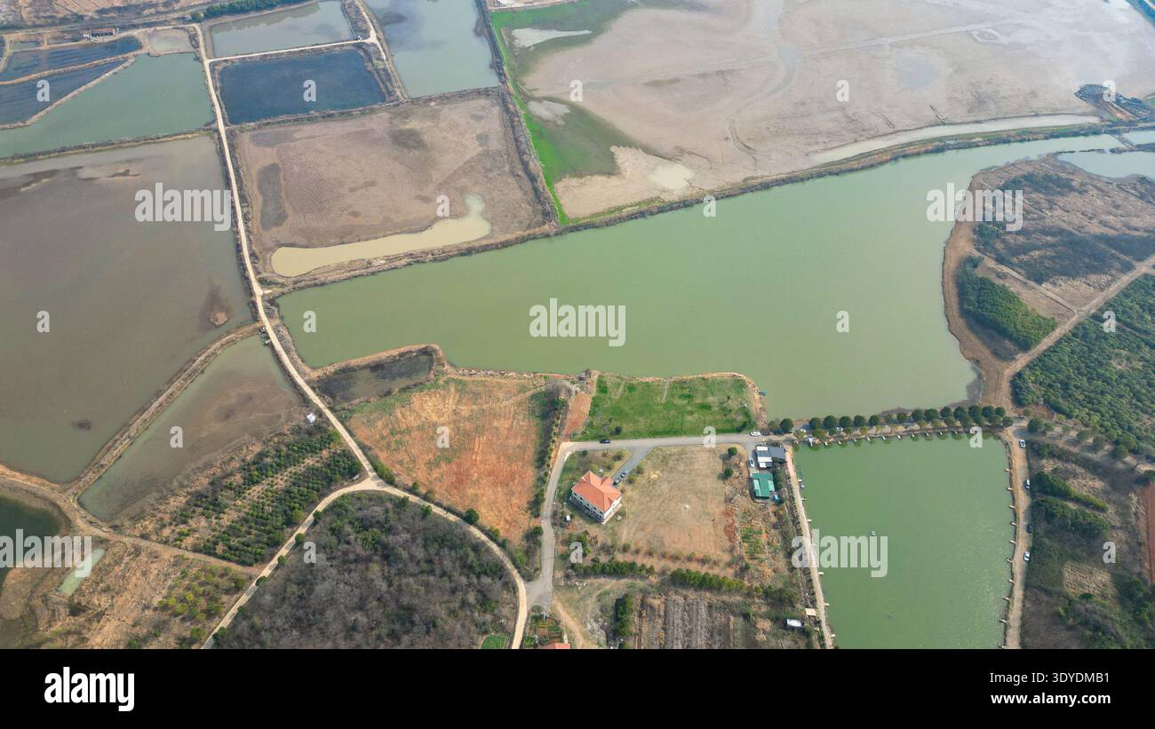 Une perspective aérienne montrant un réseau d'étangs d'eau ruraux utilisés pour l'aquaculture, entourés de champs agricoles verts. L'image transmet la nourriture pro Banque D'Images