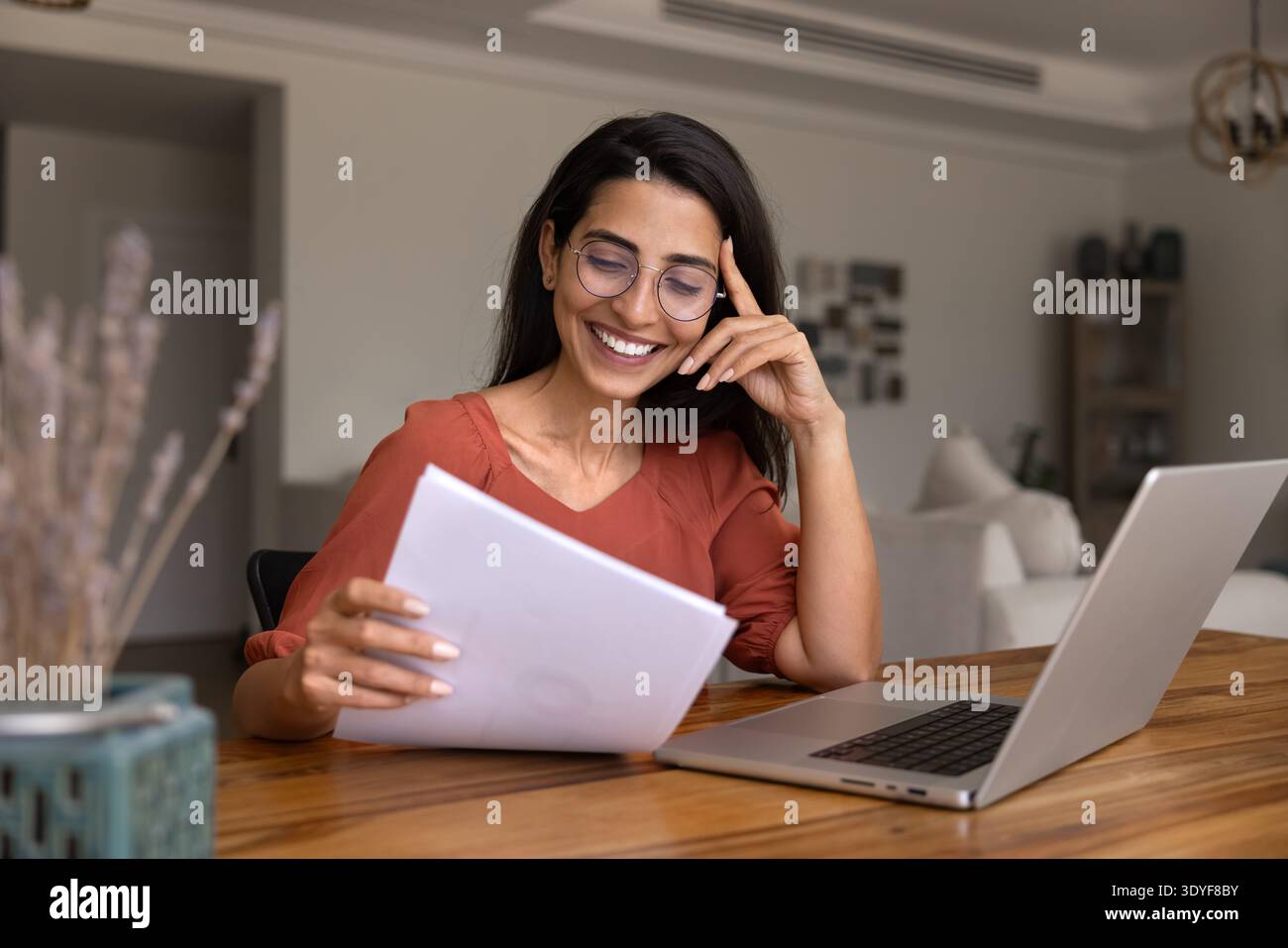 Femme tenant une pile de documents, lisant des informations avec une expression satisfaite Banque D'Images