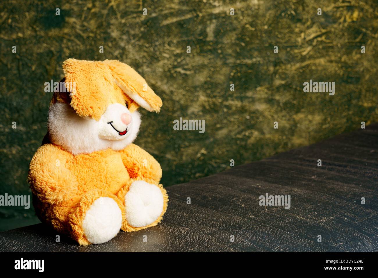 Lapin en peluche se trouve sur une surface sombre avec un fond vert dans un cadre de pièce confortable Banque D'Images