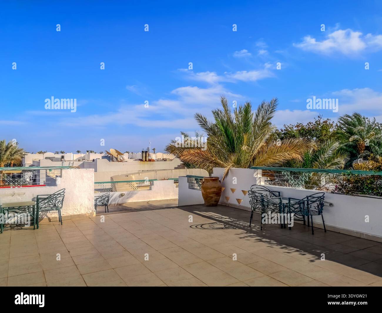 Belle terrasse avec tables sur le toit de l'hôtel à Sharm El Sheikh (Egypte). Paysage de patio exotique avec de grandes amphores d'argile et des feuilles de palmier - Image de stock capturée avec un smartphone