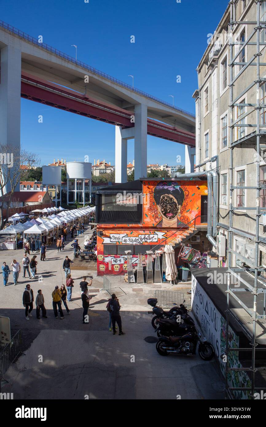 LX Factory à Lisbonne sous le pont Ponte 25 de Abril, scène urbaine dynamique avec art de rue, cafés et architecture industrielle. Banque D'Images