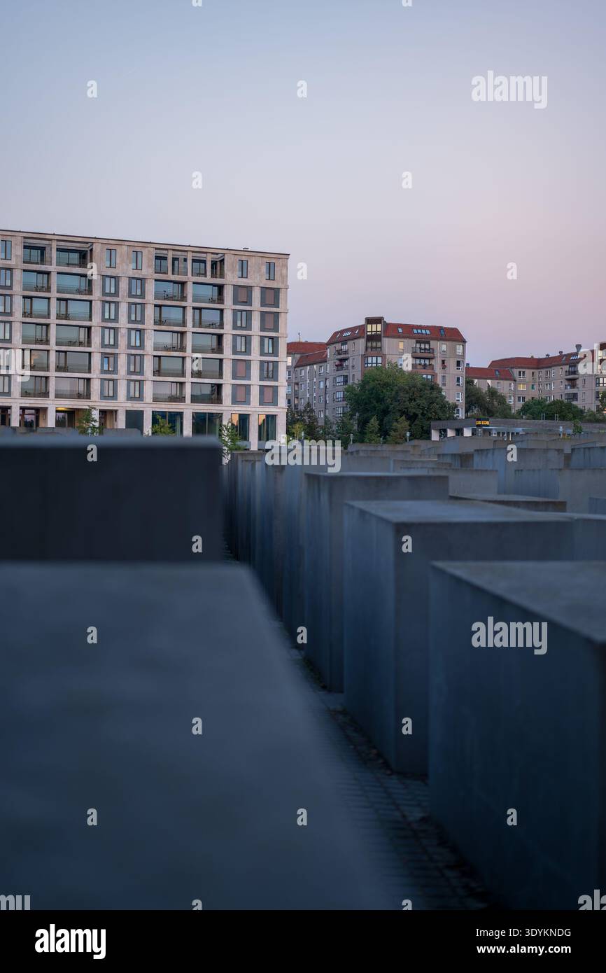Des stèles en béton forment une grille au Mémorial des Juifs assassinés d'Europe à Berlin, avec des appartements au toit rouge derrière. Perspective basse à travers étroit Banque D'Images
