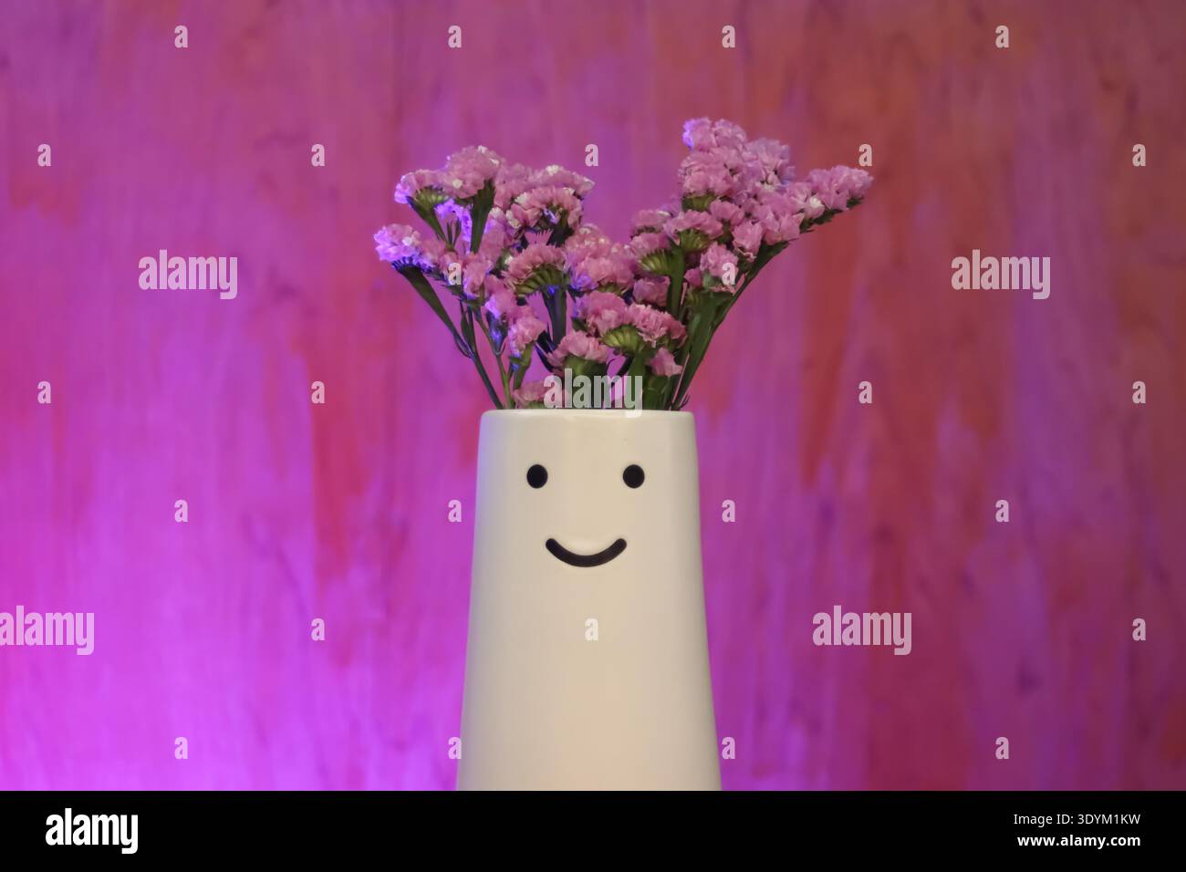 Vase minimaliste avec des fleurs roses sur fond vibrant exprimant un décor à la maison confortable et un concept de bien-être émotionnel. Banque D'Images