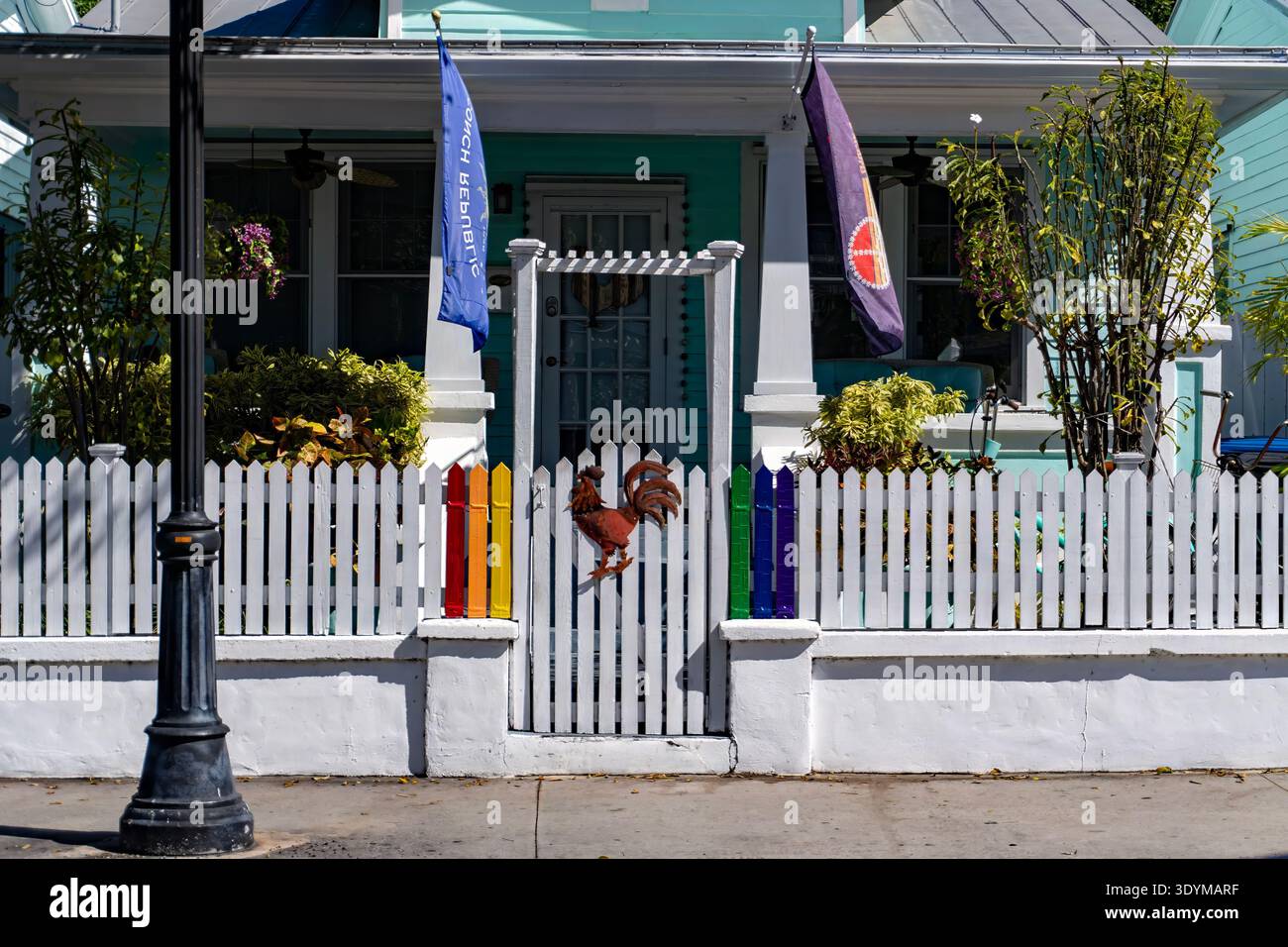 Une famille humaine : clôture de piquet colorée et drapeaux de la République de Conch gardant un Cottage Key West Banque D'Images
