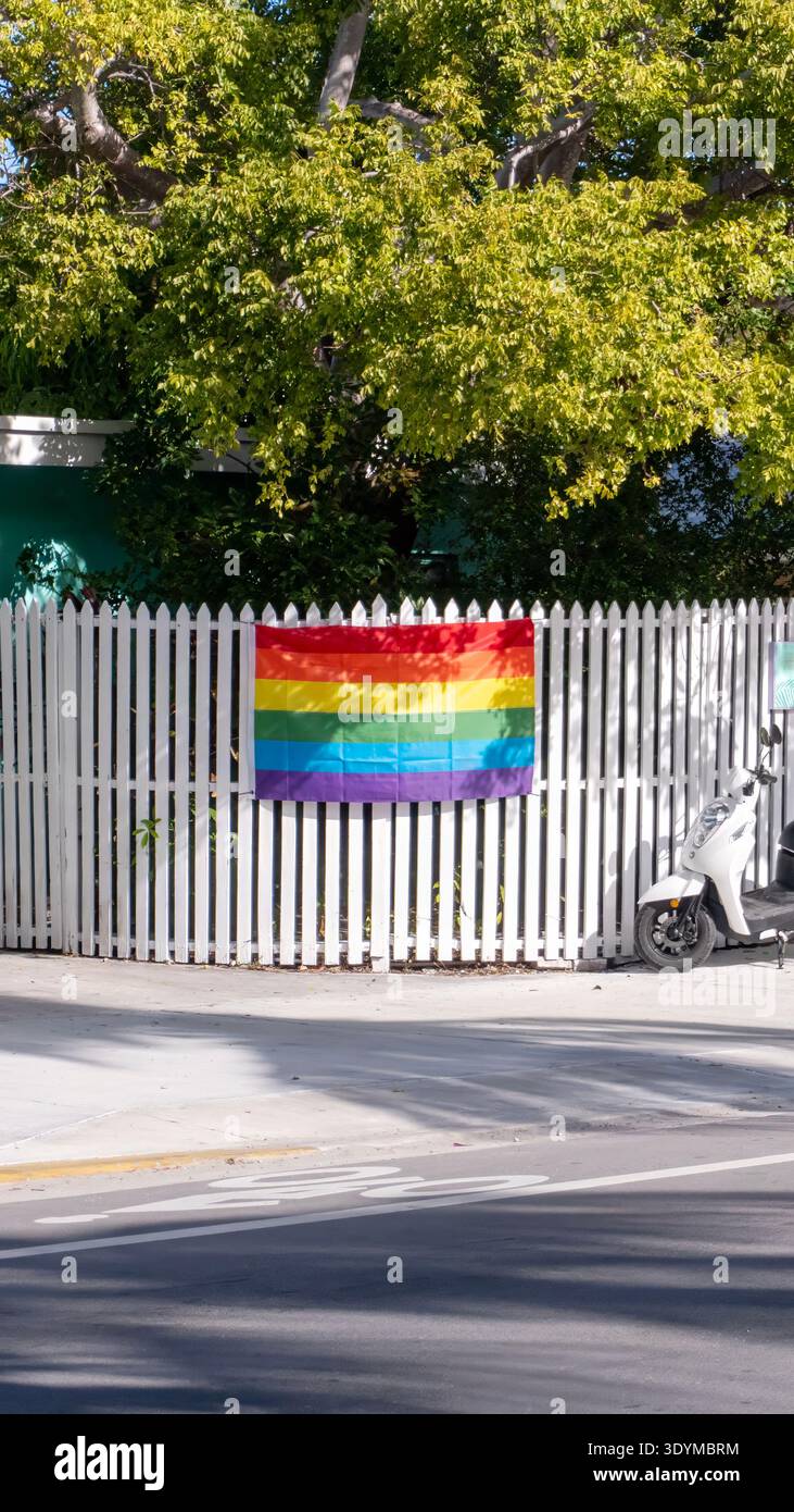 Vue verticale d'un drapeau Rainbow Pride sur une clôture de piquet blanc à Key West, en Floride Banque D'Images