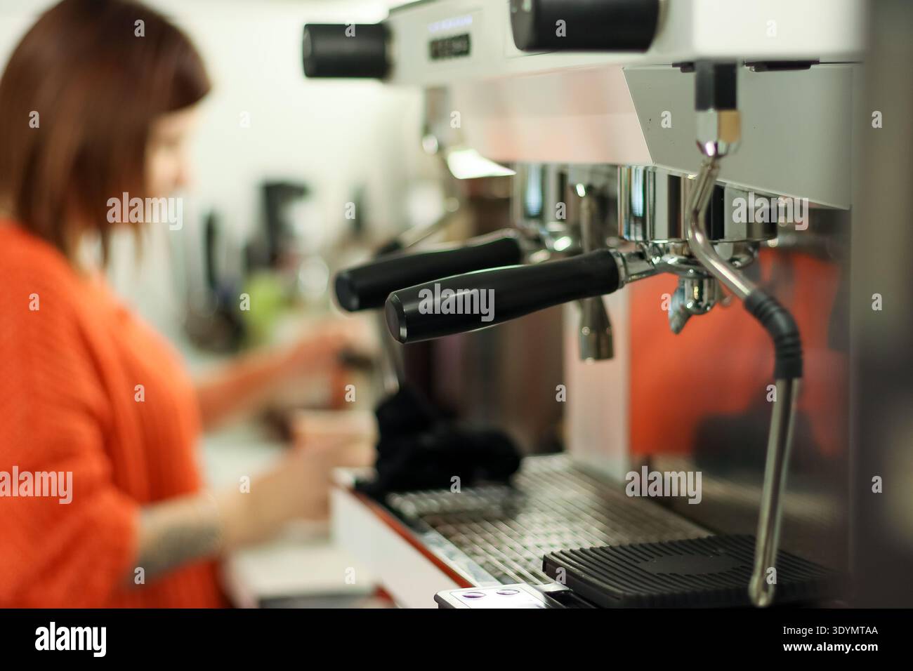 Gros plan des mains de barista utilisant une machine à espresso professionnelle pour préparer une boisson au café dans un café moderne. Banque D'Images