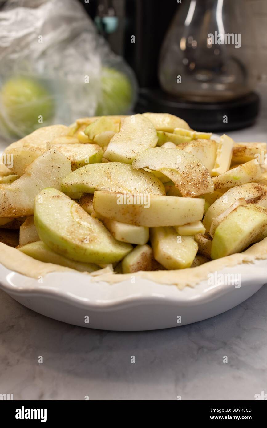 Pâte à tarte crue dans une poêle en céramique avec des pommes tranchées pour la tarte aux pommes Banque D'Images