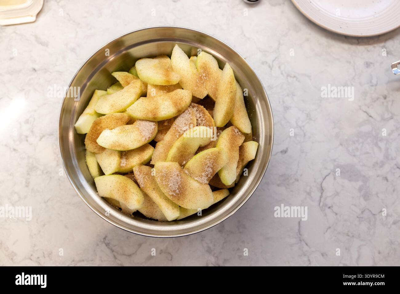 Bol de pommes tranchées pour garniture de tarte, enrobées de cannelle et de su Banque D'Images