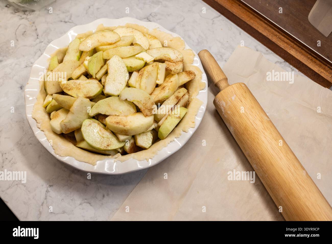 Pâte à tarte crue dans une poêle en céramique avec des pommes tranchées pour la tarte aux pommes Banque D'Images