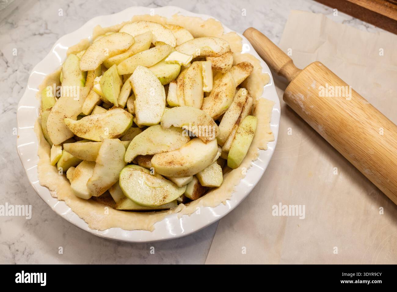 Pâte à tarte crue dans une poêle en céramique avec des pommes tranchées pour la tarte aux pommes Banque D'Images