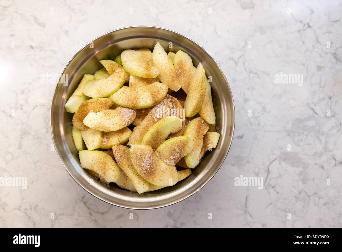 Bol de pommes tranchées pour garniture de tarte, enrobées de cannelle et de su Banque D'Images