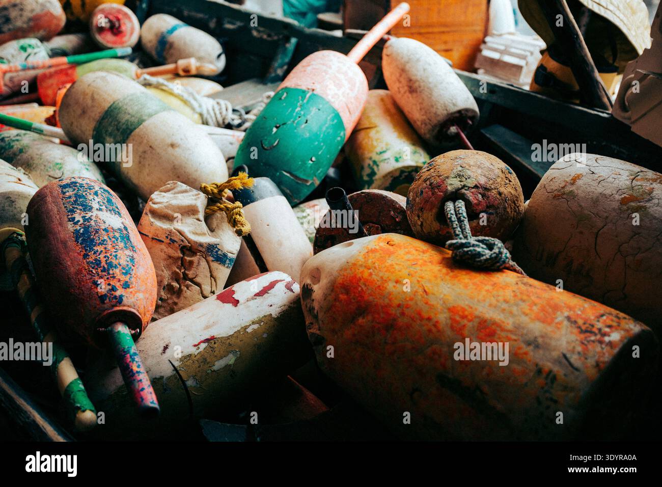 Pile de bouées colorées de homard altérées dans un bateau vert usé. Banque D'Images
