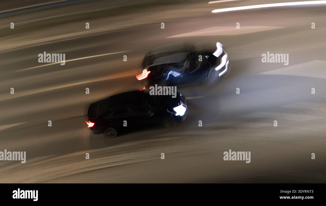 Image de mouvement floue de deux voitures entrant en collision sur une route la nuit, capturant le moment de l'impact et la vitesse de transport, le danger et le risque de circulation urbaine. Banque D'Images