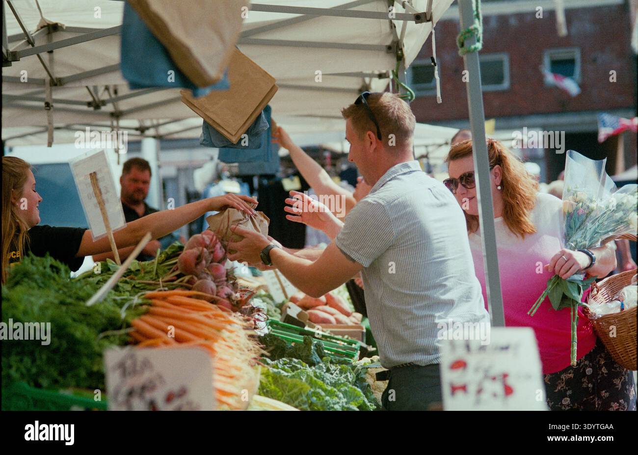 Le marché historique de Swaffham à Norfolk perpétue une tradition commerciale datant de plus de 800 ans. Tous les samedis, la place du marché regorge d'étals proposant des viandes locales, des produits frais et des objets de collection uniques à l'ombre de l'emblématique Buttercross du XVIIIe siècle. Un moment fort est la vente aux enchères en plein air de 11h00, où la sonnerie d'une cloche signale la vente d'articles ménagers éclectiques et d'outils de jardin. Le vendredi, les Assembly Rooms accueillent un marché couvert proposant des conserves faites à la main et de l'artisanat, maintenant la réputation de la ville en tant que plaque tournante pour le commerce rural. Banque D'Images