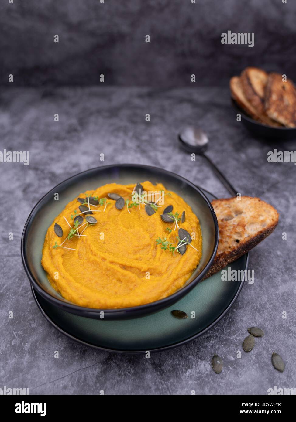 Vue rapprochée de la soupe crémeuse à la citrouille avec du pain grillé dans une cuisine rustique et de mauvaise humeur Banque D'Images