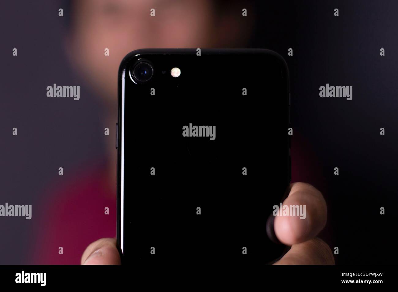 Jeune homme tenant un téléphone portable, smartphone, avec la main et le fond flou Banque D'Images