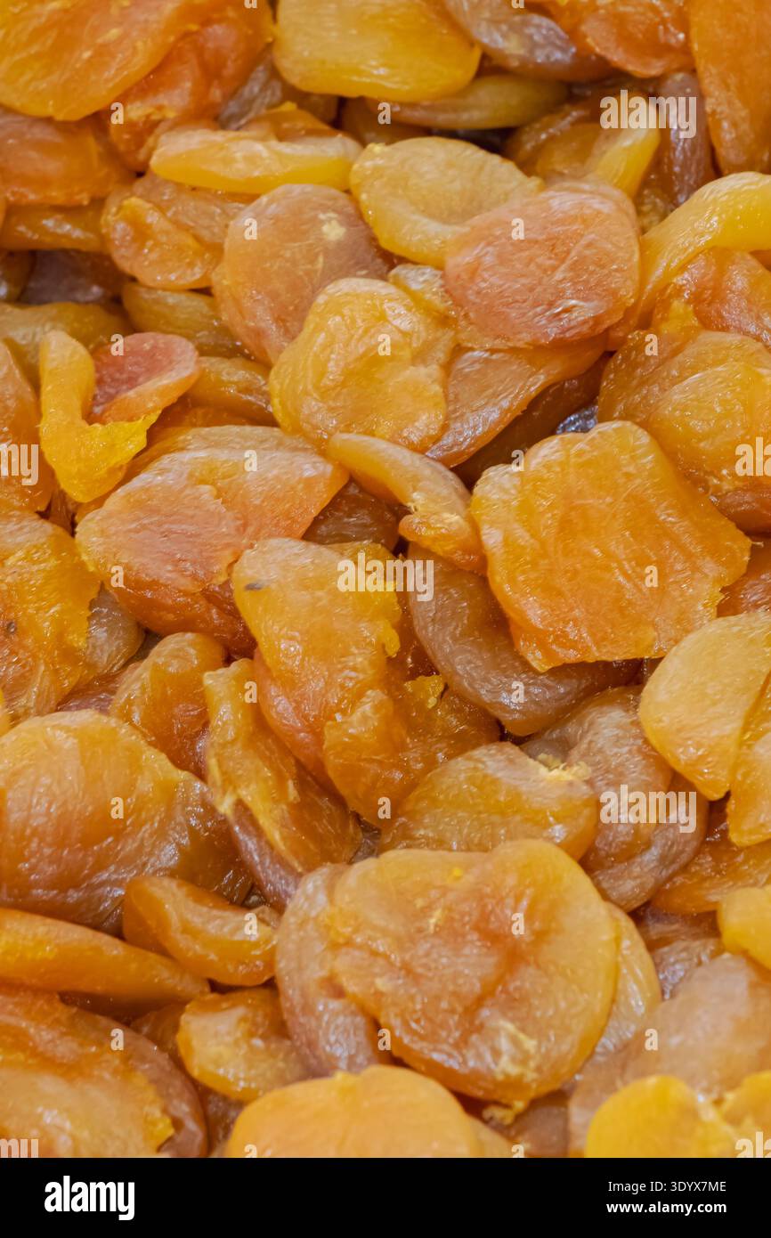 Gros plan d'abricots séchés empilés ensemble à un étal de marché, mettant en évidence la couleur orange naturelle, la texture froissée et la collation saine aux fruits secs. Banque D'Images