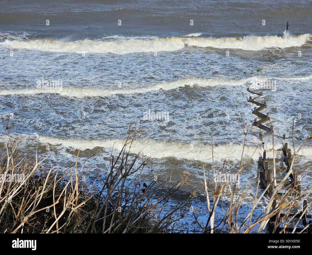 Overstrand Shoreline, Norfolk. Regardant vers le bas depuis les falaises, les groynes pour l'atténuation de l'érosion côtière sont entièrement couverts à marée haute et la plage i. - Image de stock capturée avec un smartphone