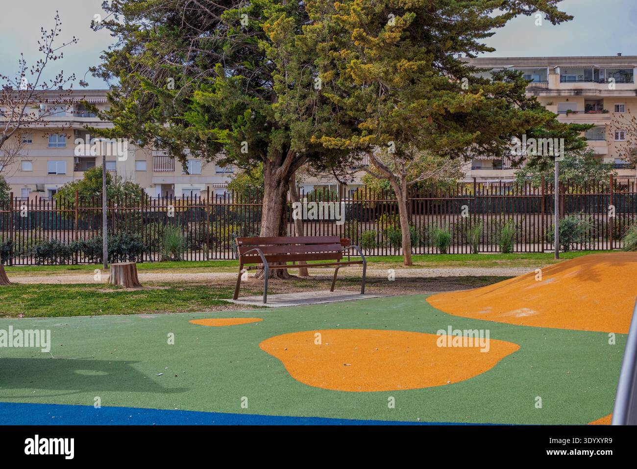 Parc urbain avec un banc en bois et un sol résilient avec des bâtiments en arrière-plan Banque D'Images