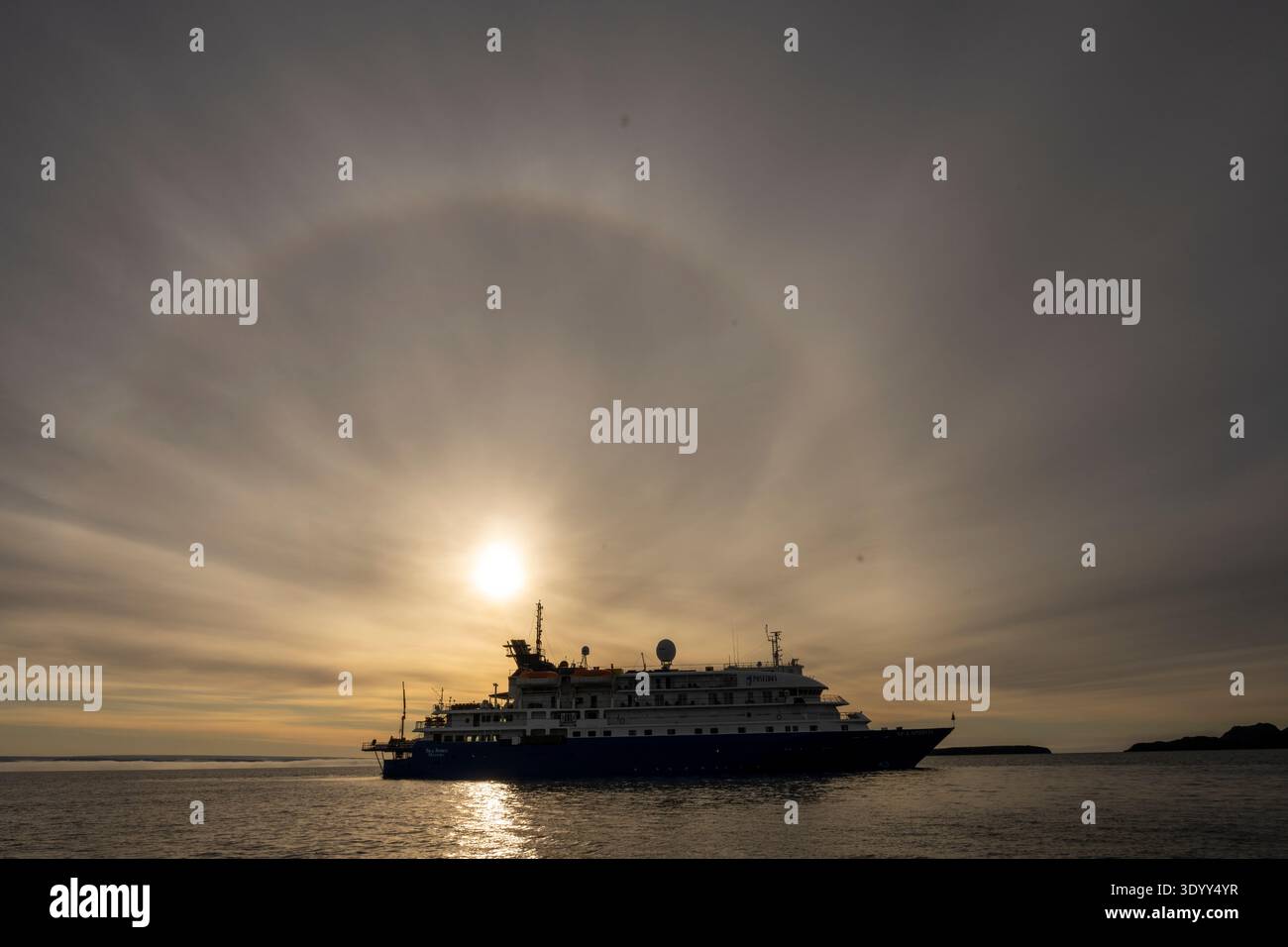 Le soleil levant avec halo et nuages striés domine la silhouette du navire de croisière Sea Spirit (Poseidon Expeditions), Alkefjellet, Banque D'Images