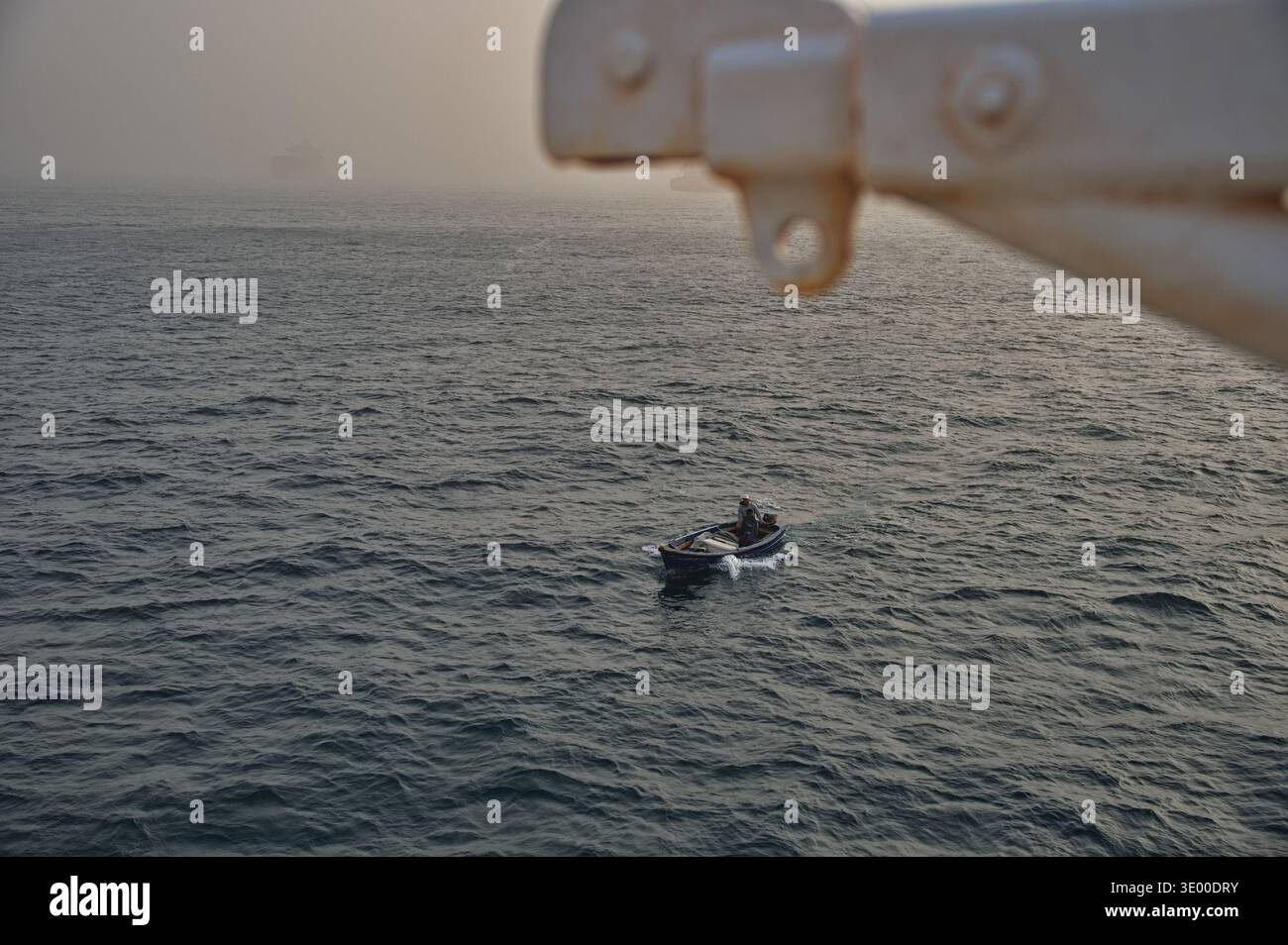 Petit bateau en bois naviguant sous un grand bateau Banque D'Images