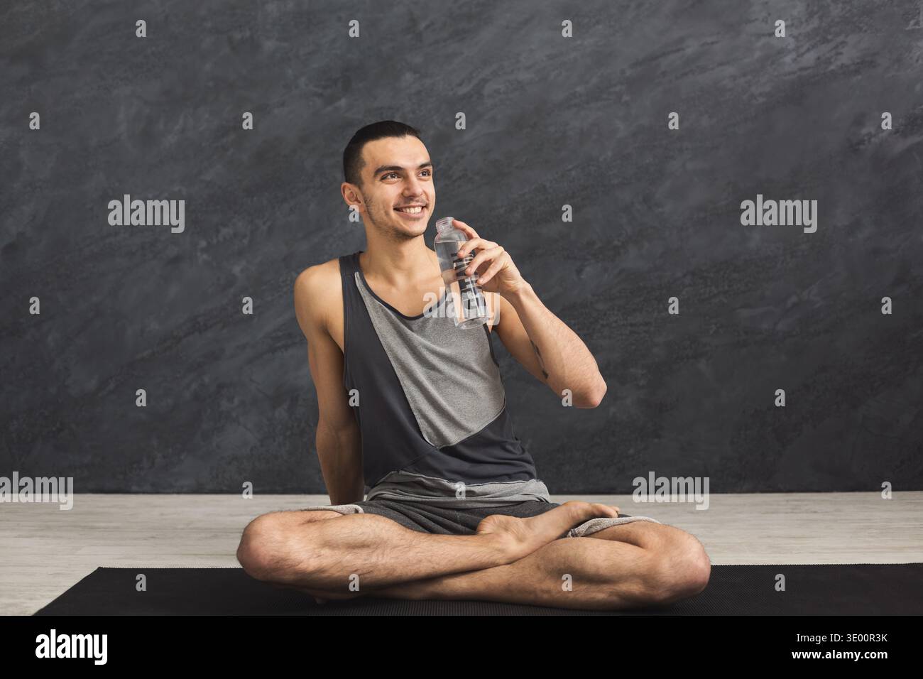 Homme de fitness buvant de l'eau au gymnase Banque D'Images