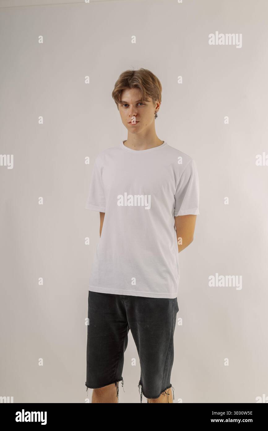 Beau jeune gars dans des vêtements élégants sur fond blanc dans le studio photo posant pour la caméra Banque D'Images