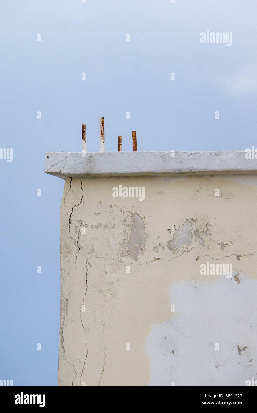 Mur de bâtiment altéré avec des fissures et armatures rouillées exposées contre un ciel bleu à Rhodes, Grèce. Banque D'Images