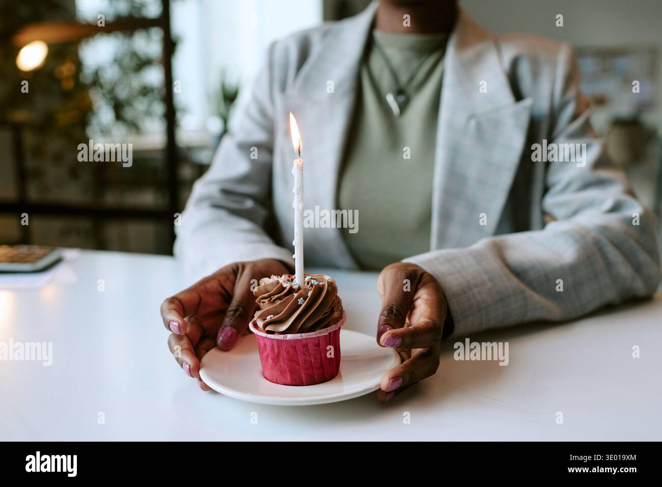 Jeune adulte femme noire tenant Cupcake avec bougie allumée célébrant l'anniversaire Banque D'Images