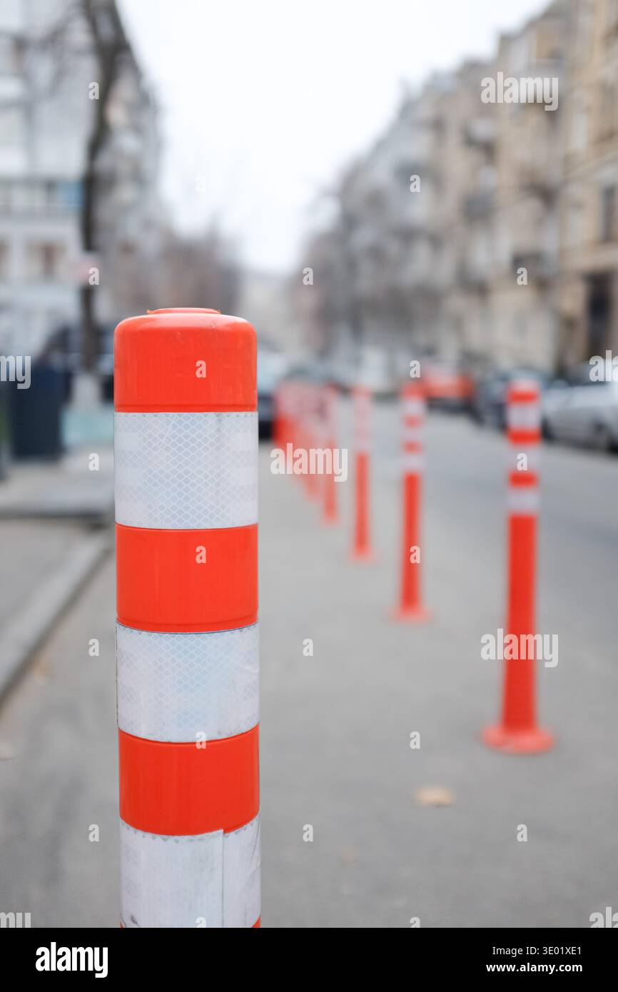 Rangée de bornes de circulation orange et blanche guidant les véhicules le long d'une rue de la ville. Banque D'Images