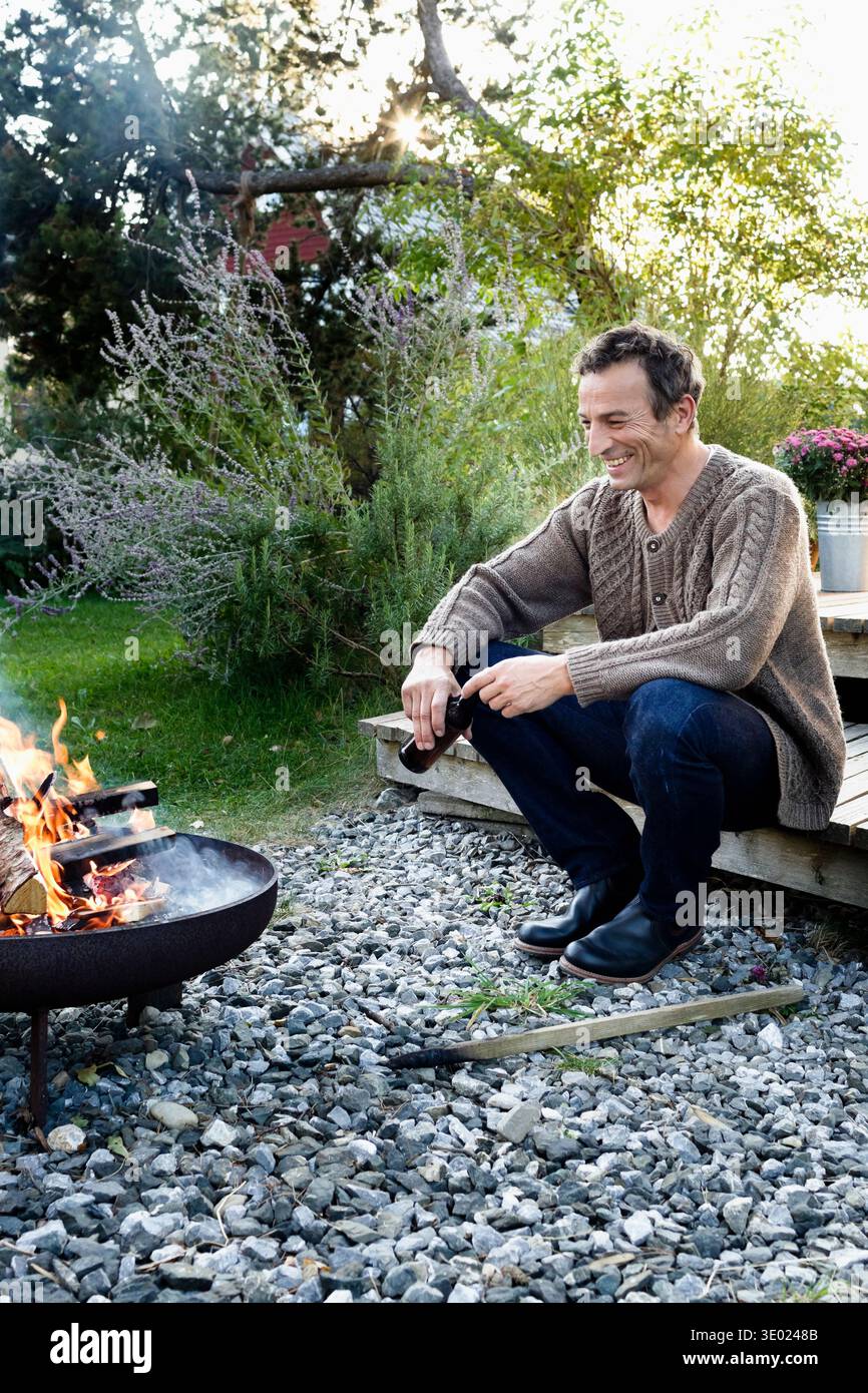 Young par feu de camp avec de la bière, de détente Banque D'Images