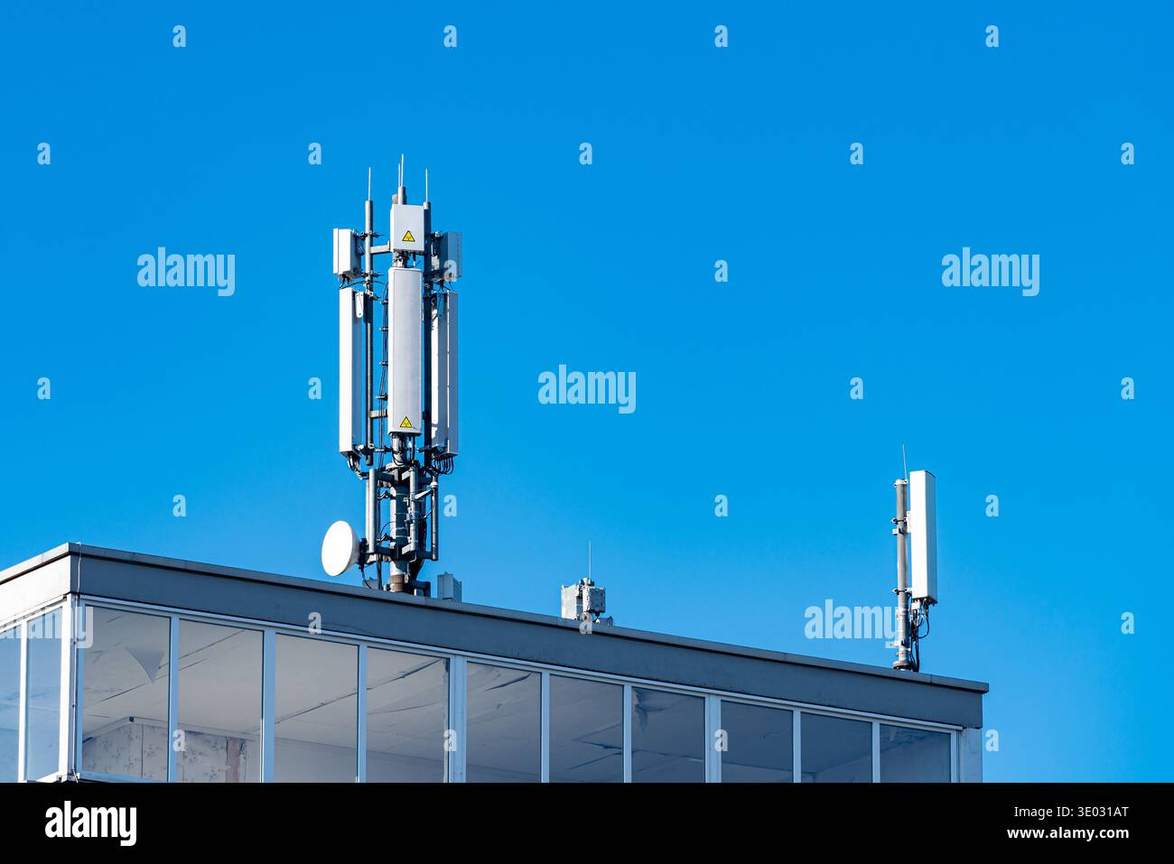 Deux tours de télécommunication se dressent au sommet d'un bâtiment sous un ciel bleu clair. Les tours sont des équipements utilisés pour les réseaux mobiles et les signaux, montrant Banque D'Images
