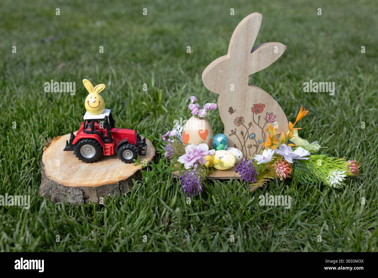 Décoration de Pâques avec lapin en bois, fleurs et oeufs près du tracteur rouge jouet. Bonne carte de Pâques pour l'agrobusiness Banque D'Images