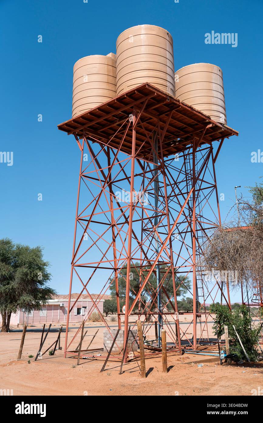 Un groupe de réservoirs d'eau cylindriques repose sur une structure métallique robuste contre un ciel bleu clair dans la Namibie rurale, mettant en évidence les infrastructures dans une zone aride Banque D'Images