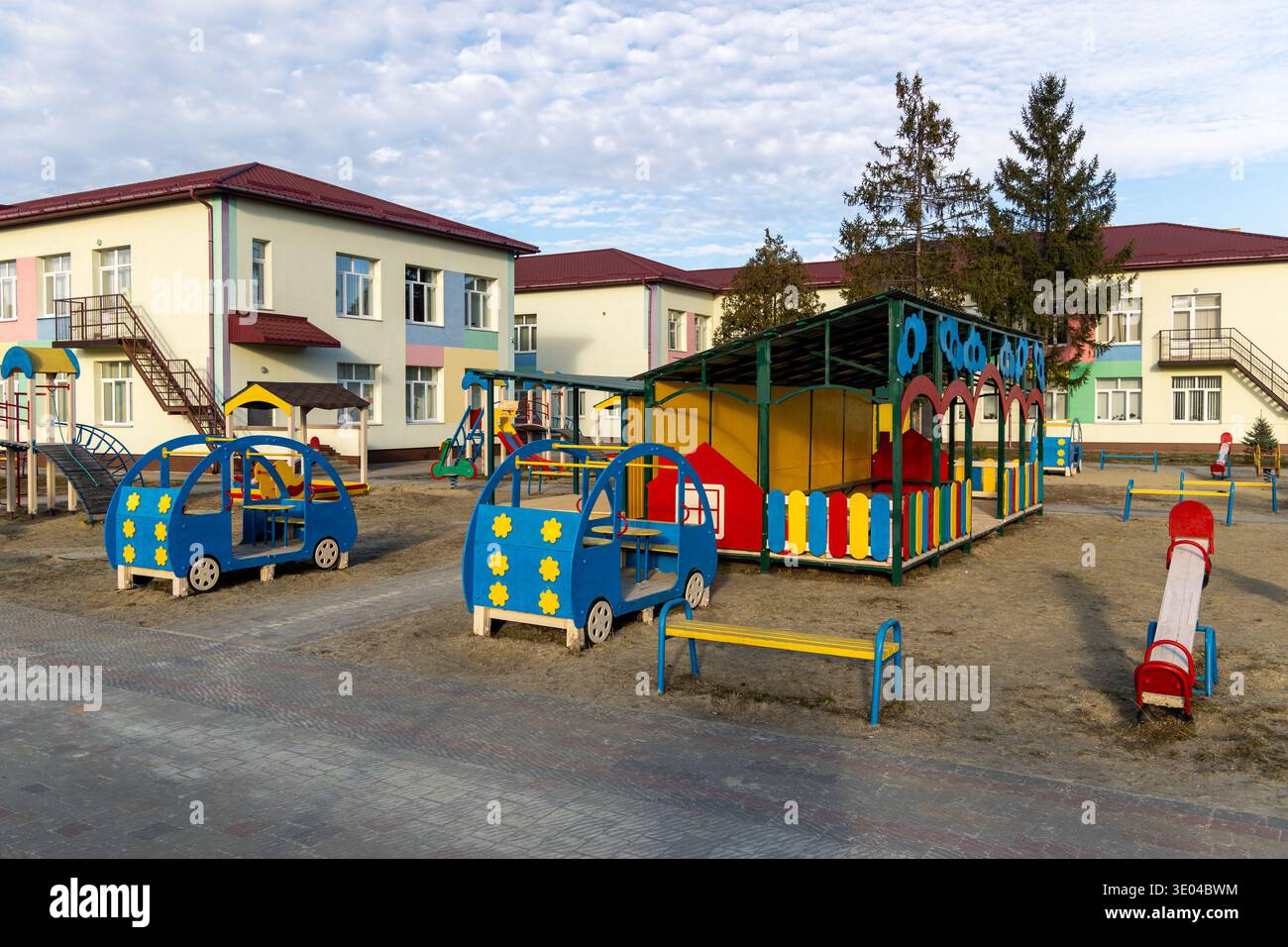Terrain de jeu coloré de la maternelle devant l'école. Aire de jeux vide de jardin d'enfants avec équipement de jeu lumineux et bâtiments scolaires, montrant un coffre-fort Banque D'Images