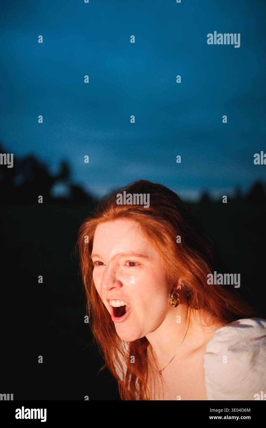 Portrait expressif d'une femme criant dans le crépuscule Banque D'Images
