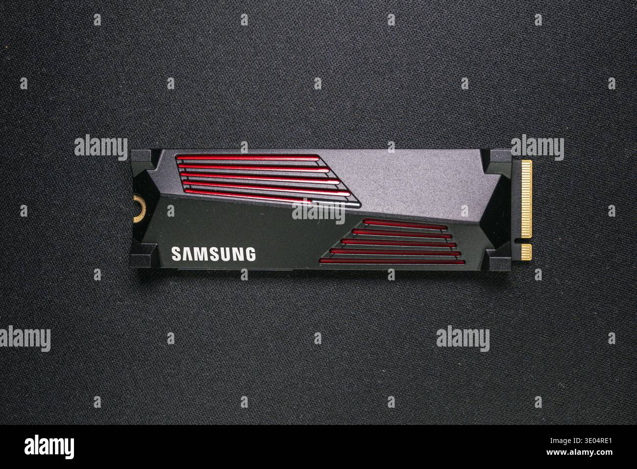 Gros plan d'un disque SSD Samsung NVMe avec des accents rouges sur une surface de tissu sombre, mettant en valeur la technologie de mémoire informatique moderne Banque D'Images