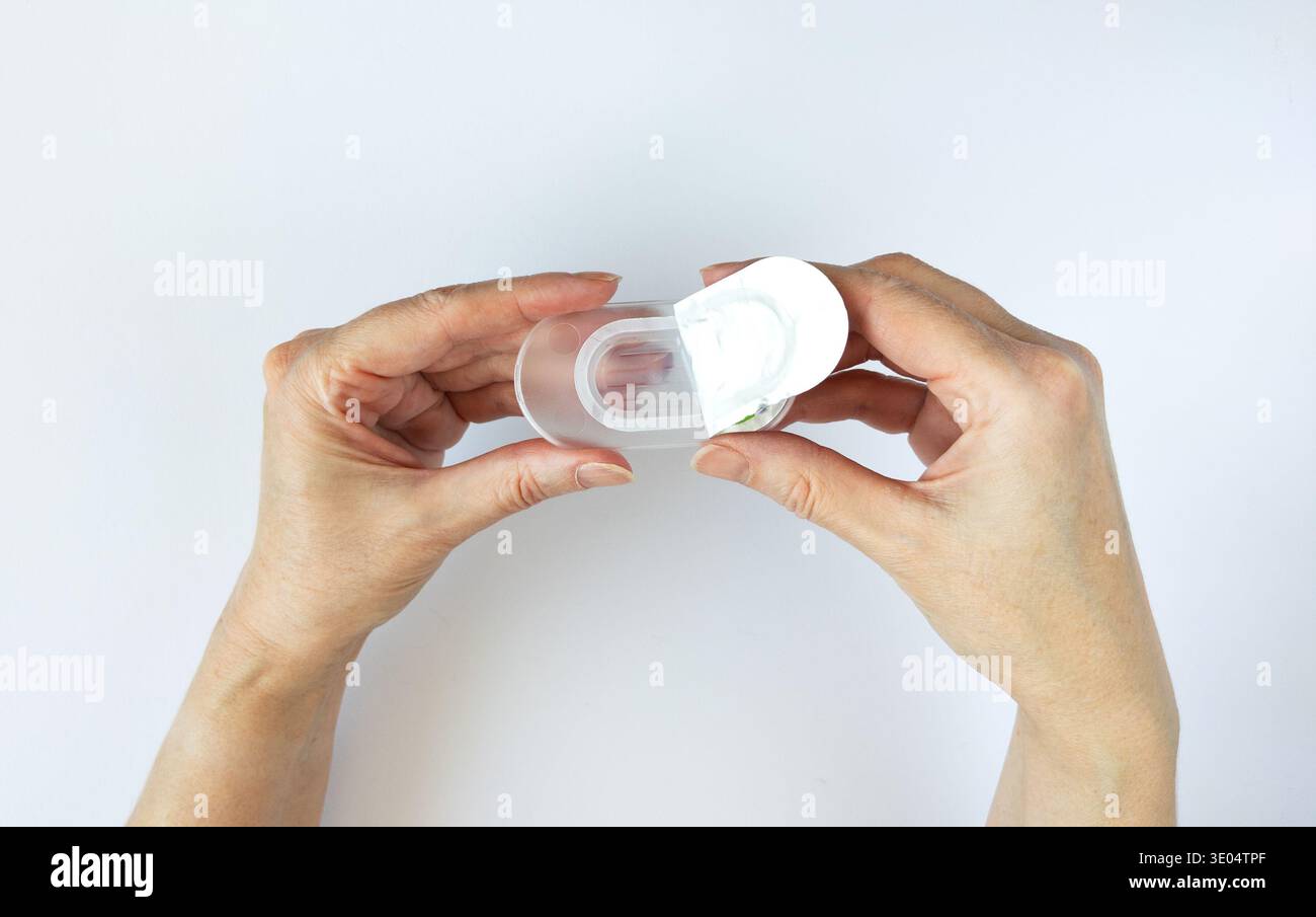 Gros plan des mains ouvrant un nouvel emballage de lentilles de contact. Les mains de la femme tiennent un blister en plastique ouvert contenant une lentille de contact. Concept pour oeil Banque D'Images