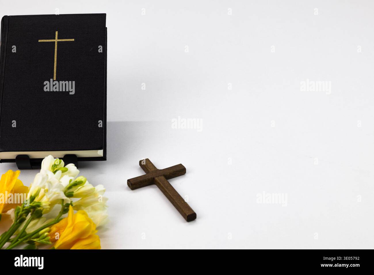 Sainte Bible avec croix et fleurs de printemps sur fond blanc, concept de foi chrétienne Banque D'Images