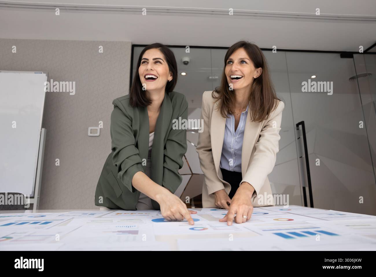 Des femmes heureuses se tiennent à table couvertes de tableaux et de graphiques Banque D'Images