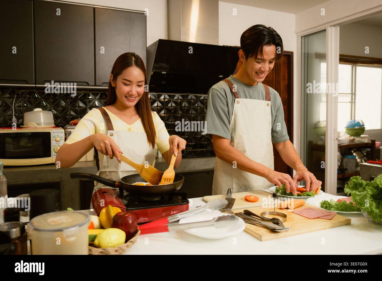 Asiatique jeune couple cuisinant dans la cuisine à la maison Banque D'Images
