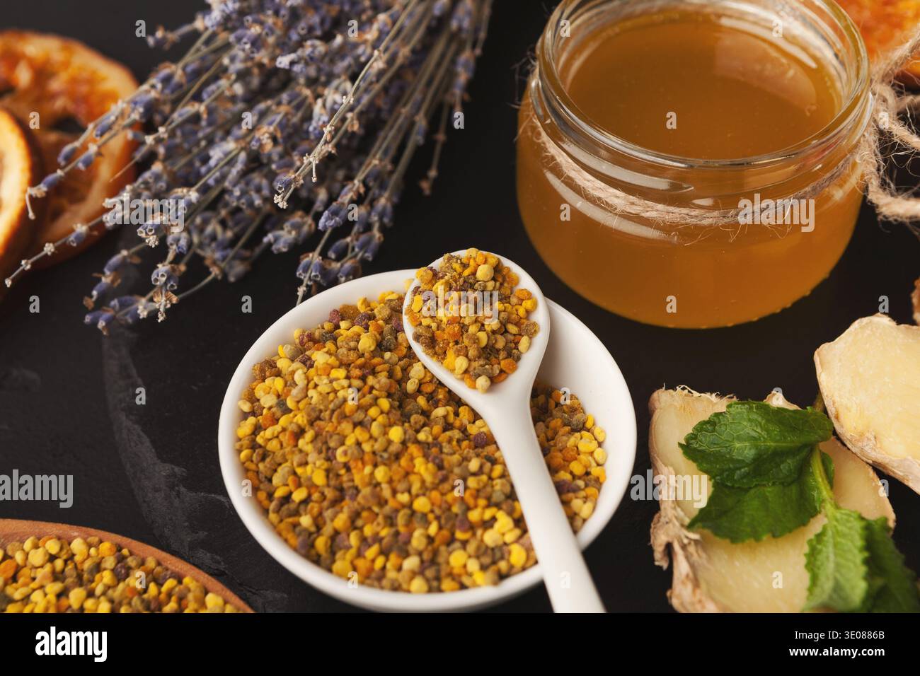 Collage de produits alimentaires avec miel, pollen, gingembre et herbes séchées sur une surface sombre Banque D'Images