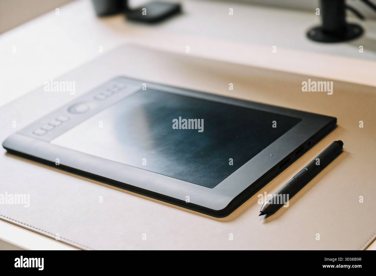 Une tablette graphique professionnelle et son stylet sont placés sur un tapis de couleur neutre, suggérant un espace de travail d'art numérique ou de design Banque D'Images