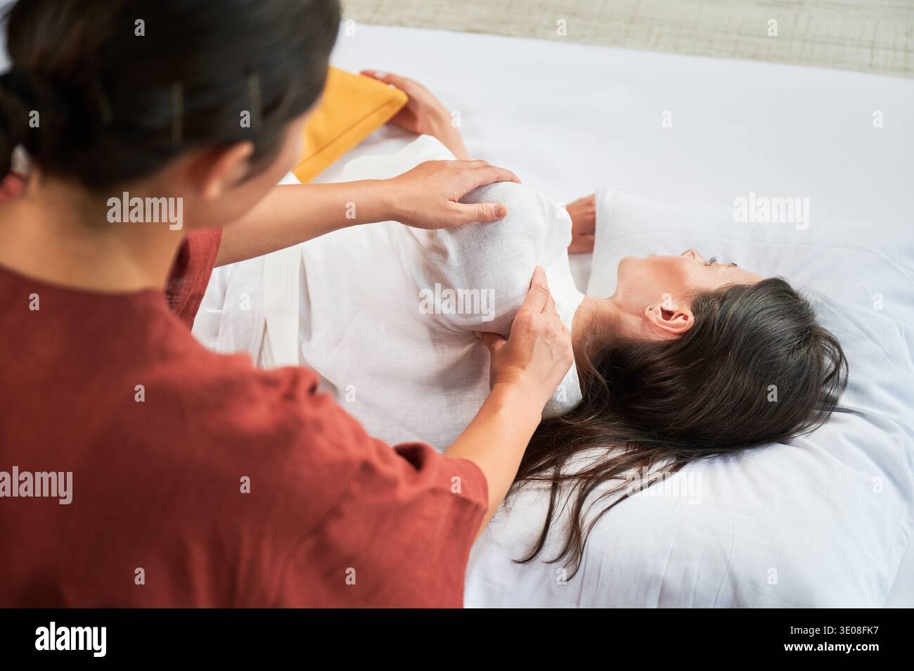 Masseuse faisant massage yoga thaïlandais. Femme thérapeute faisant le traitement de massage traditionnel pour la patiente féminine. Client allongé sur tapis, méditant, profitant d'un massage des mains dans une atmosphère calme. Vue rognée. Banque D'Images