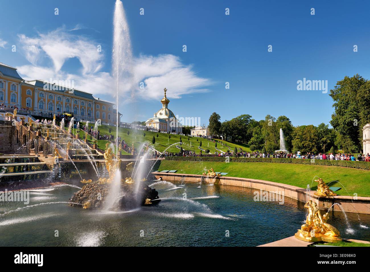 Les gens se rassemblent pour voir les fontaines du palais Peterhof à Saint-Pétersbourg. Le soleil brille sur le palais et les jardins. Banque D'Images