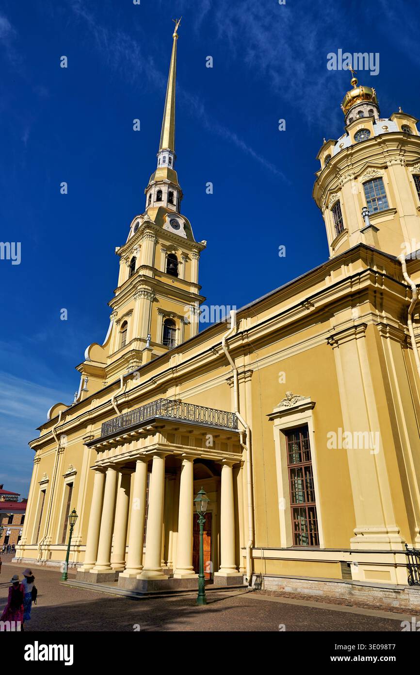 Les visiteurs marchent près de la cathédrale Pierre et Paul à Peter et Paul Fortress à Pétersbourg, Russie. Le ciel est bleu et clair. Banque D'Images