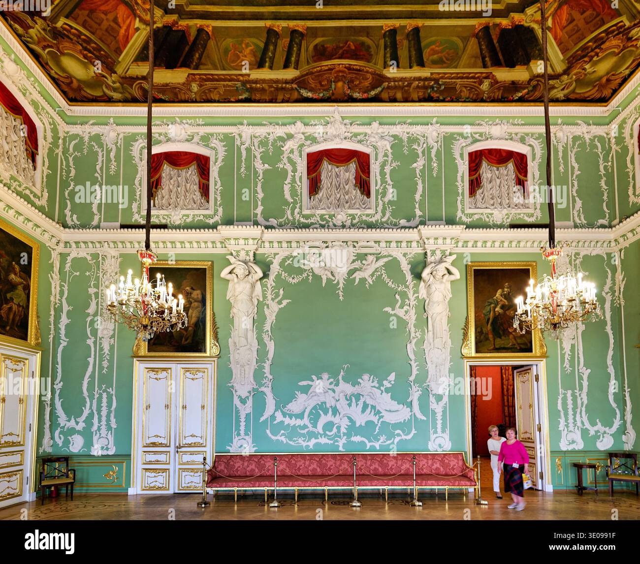 Deux personnes traversent le palais Stroganov, observant l'art et le décor dans la salle. L'espace montre de beaux éléments de design. Banque D'Images
