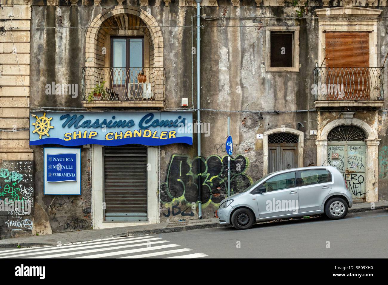 Un navire Chandler magasin dans la via Vecchia Dogana, Catane, Sicile, Italie. Le magasin est fermé, dans une rue urbaine avec des graffitis sur les murs. Banque D'Images