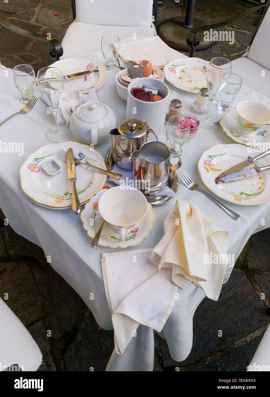 Après le petit déjeuner, table de tasses en porcelaine vintage et assiettes florales sur une nappe en lin blanc avec service de thé en argent Banque D'Images