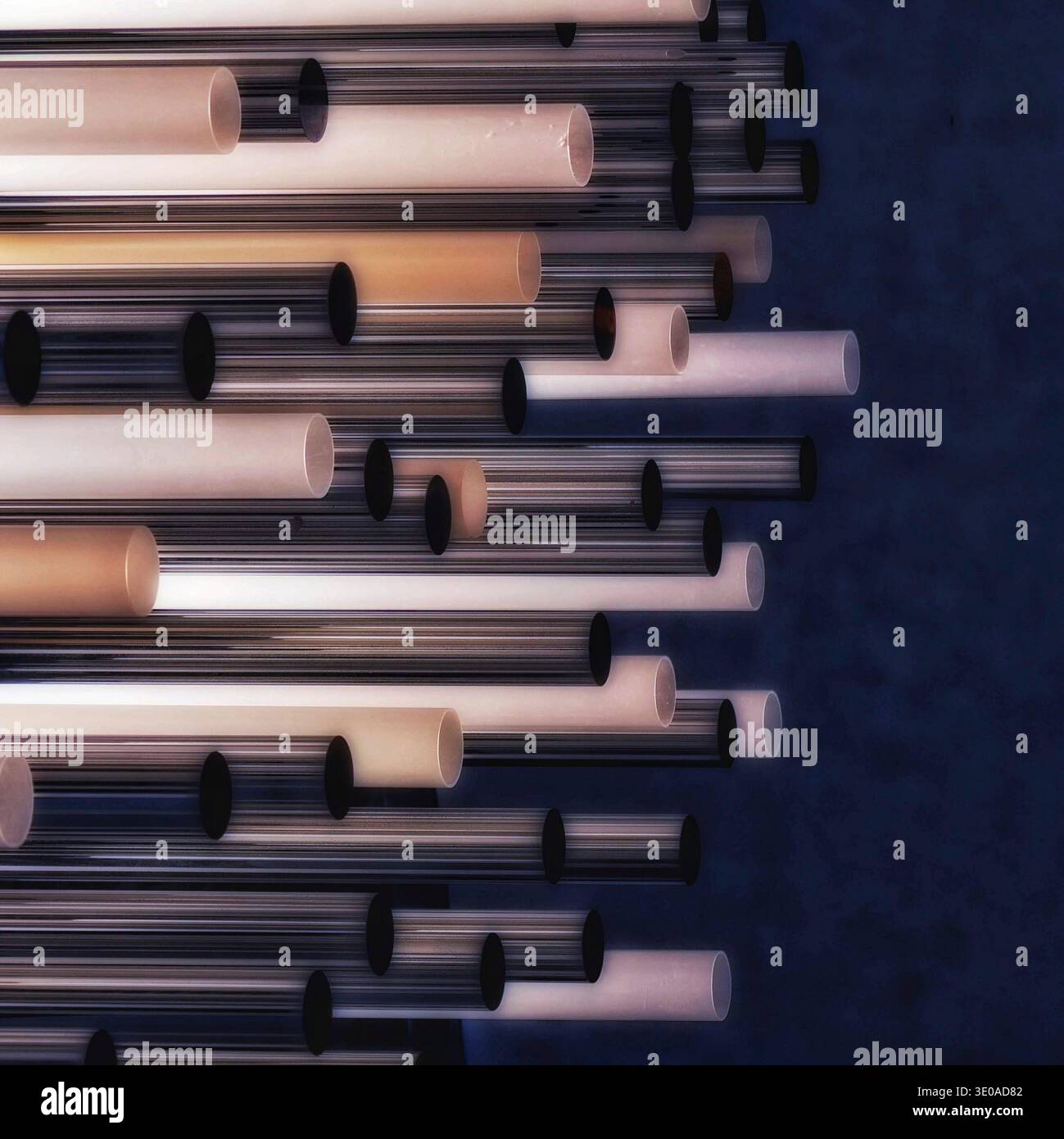 Photographie expérimentale, arrangement dense de tubes en plastique horizontaux, certains éclairés avec une lueur interne chaude, sur fond indigo profond. Banque D'Images